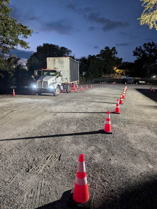 A student backing a straight truck through the cone course at dusk