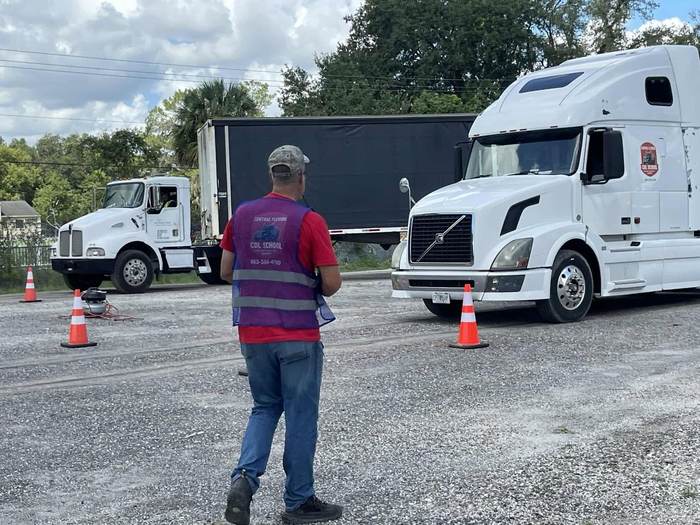 An instructor watching a student navigate the backing cone course