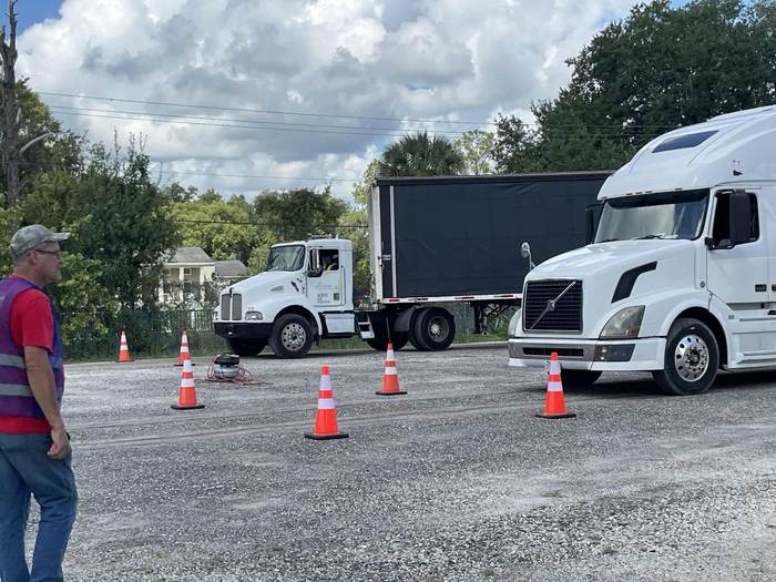 Two training trucks maneuvering through the cone course on the practice lot