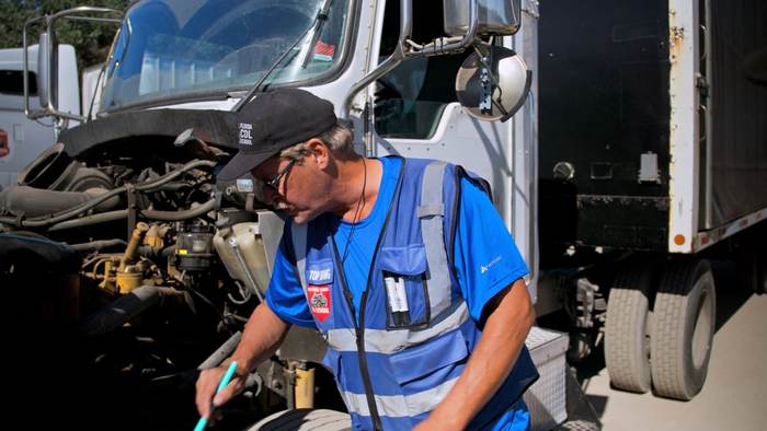 A Central Florida CDL School instructor performing a pre-trip inspection on a truck engine bay
