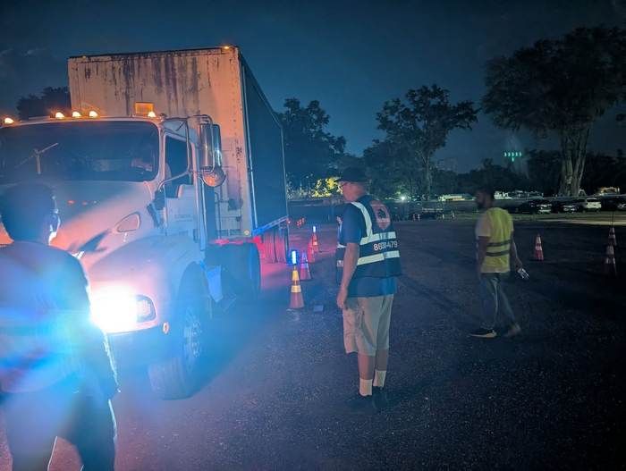 Students and an instructor during an evening CDL training session on the lit practice lot