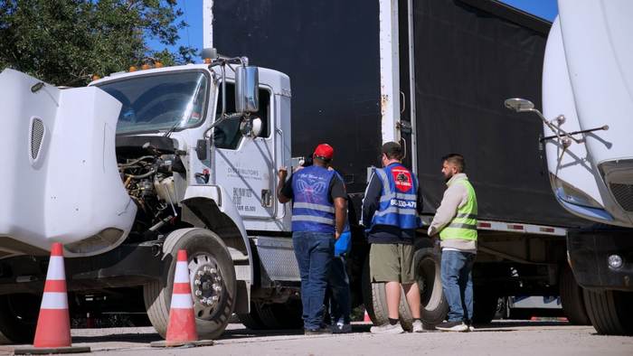 Students and an instructor doing a pre-trip walkaround inspection between two training trucks