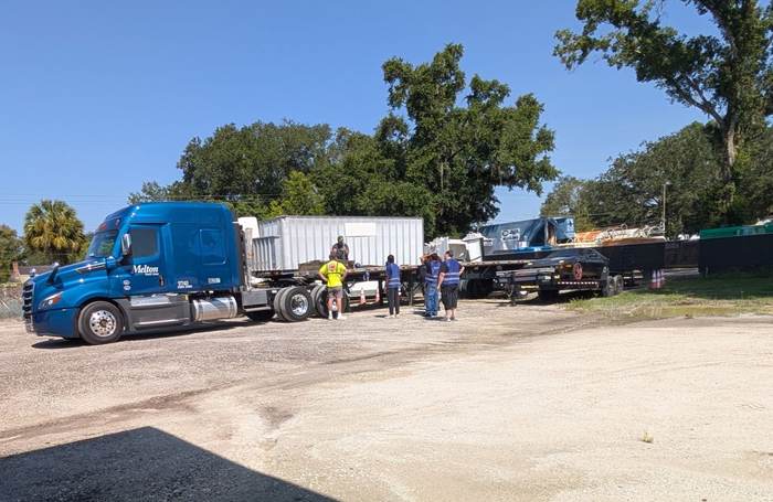 A Melton Truck Lines flatbed and a car-hauler trailer parked in the Central Florida CDL School training yard