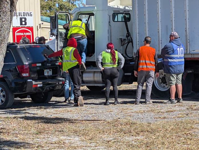A prospective student climbing into a truck cab while others watch during a free session